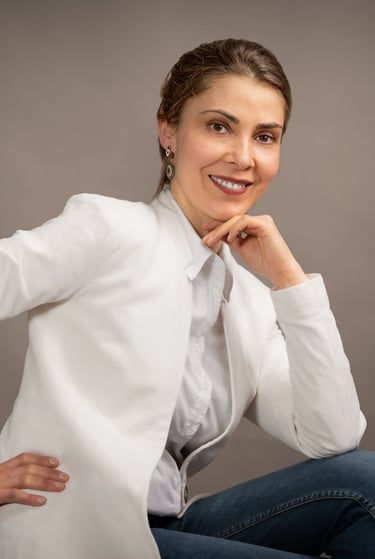 a corporate woman placing her amount on her handin a white shirt and jeans sitting on a chair