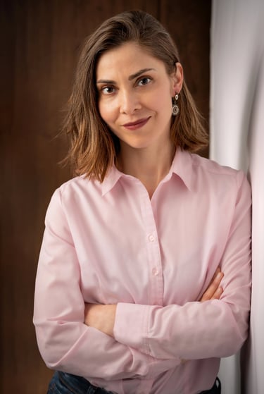 a corporate woman in a pink shirt and jeans leaning against a wall