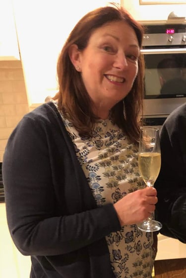 Two adults celebrating birthday in modern kitchen with champagne and cake reading 'Happy Birthday
