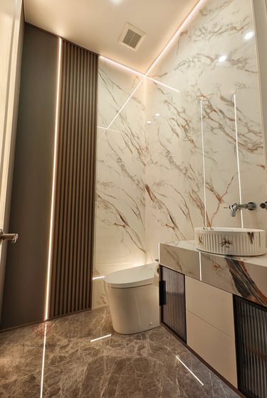 Sleek bathroom interior with seamless marble wall slabs, brushed gold metal trim accents, and a smar