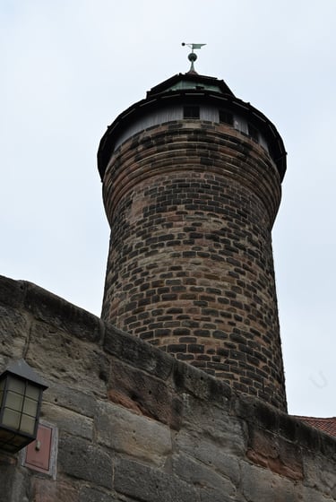 Medieval stone tower at Nuremberg Castle with historic defensive walls and a cloudy sky.