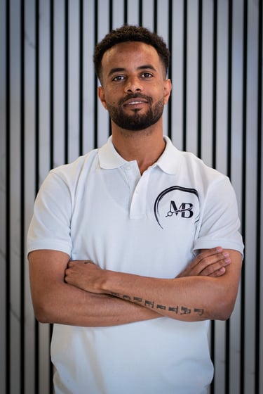 well lit Portrait photo of Ben, Co-owner of MB Barbers Manchester, posing with a smile and his arms crossed