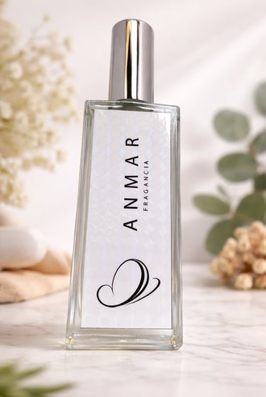 Elegant glass bottle of Anmar Fragancia perfume displayed on a marble surface with eucalyptus leaves.