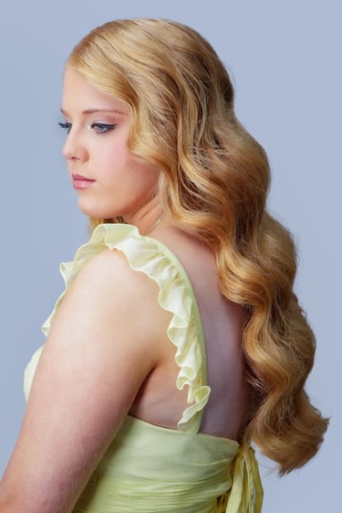 Bride with redhead hair styled in glam waves, wearing yellow dress, soft wedding makeup with neutral tones and long lashes.