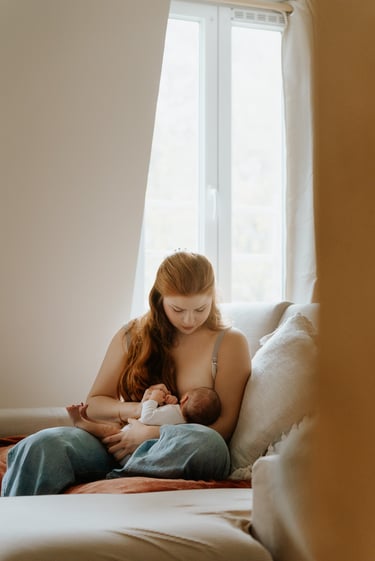 portrait de femme assise sur un canapé allaitant un bébé lumière douce en intérieur