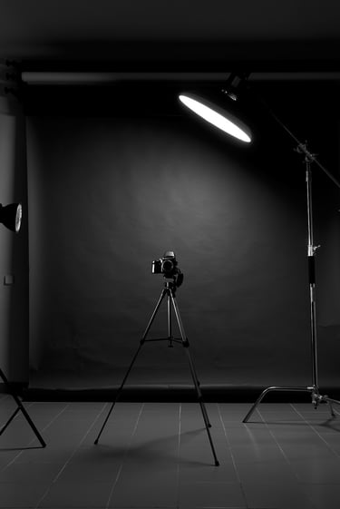 Professional photography studio setup with DSLR camera on a tripod and overhead studio lighting equipment.