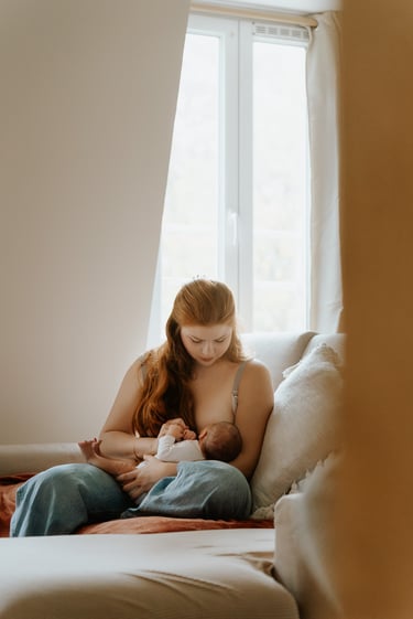 portrait de femme assise sur un canapé allaitant un bébé lumière douce en intérieur