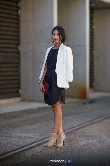 a woman in a black dress and white jacket