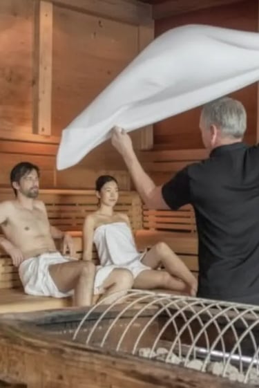 A professional sauna master performing a traditional Aufguss ceremony in a wooden sauna at Aqua Dome