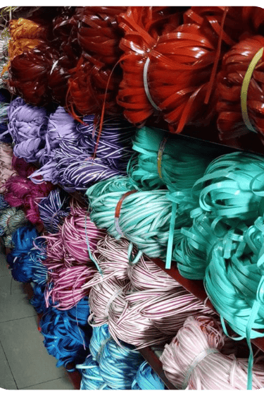 Bundles of multi colored recycled plastic weaving strips neatly stored and ready for handmade woven bag production.