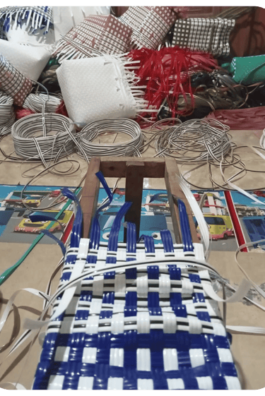 Shaping the base of a yellow and white handmade woven bag using recycled plastic weaving strips at Craftvitas Indonesia.