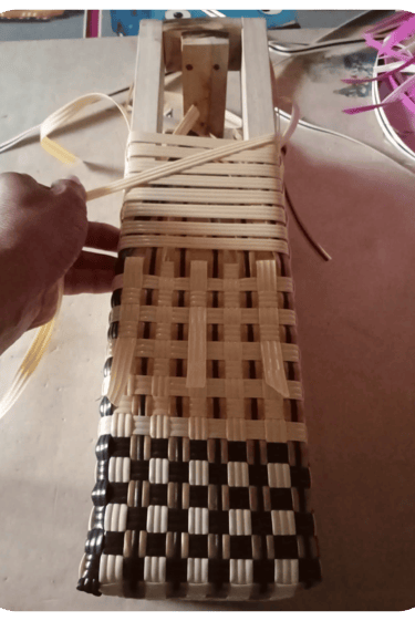 Ongoing weaving process of a blue and white handmade plastic woven bag at Craftvitas Indonesia workshop.