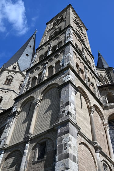 Low angle view of the Romanesque stone towers and spires of the historic Bonn Minster cathedral in Germany.
