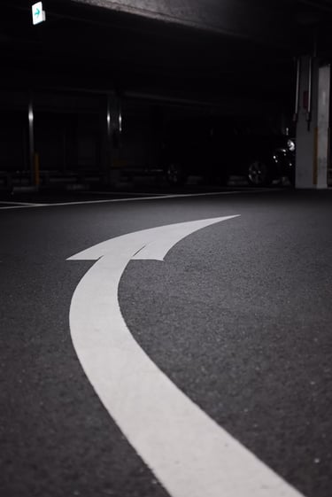 Una figura de una flecha curveada hacia la derecha y pintada sobre el pavimento.