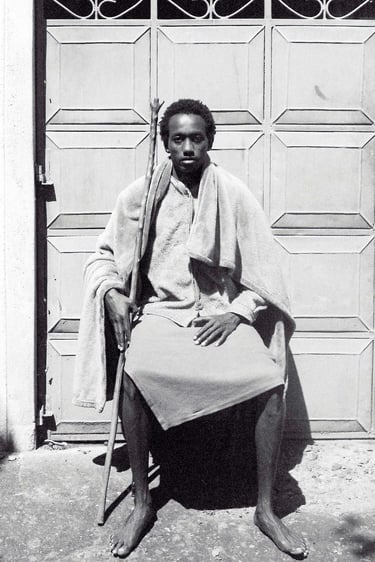 Manjahi Njoroge, a man sitting on a chair in front of a door