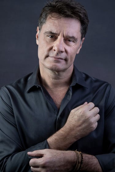 Ator vestindo camisa cinza em fundo cinza para ensaio em estúdio , posando cruzando os braços