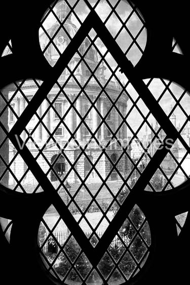 Black and white view of the Radcliffe Camera in Oxford through a gothic quatrefoil window.