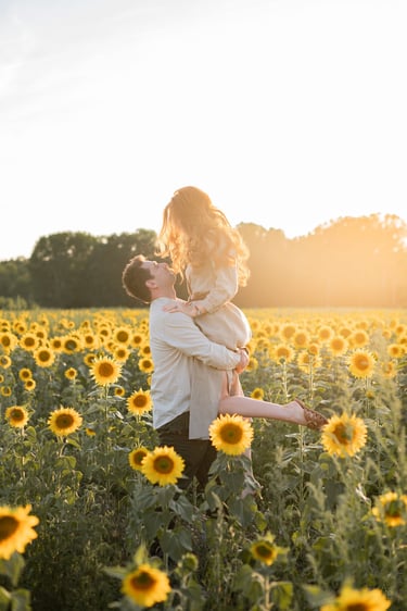 Un homme porte une femme dans un champ de tournesols au coucher du soleil