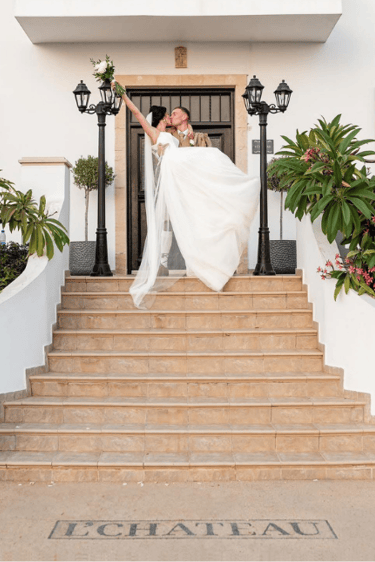 Bride and groom kissing on entrance steps at L'Chateau wedding venue Paphos