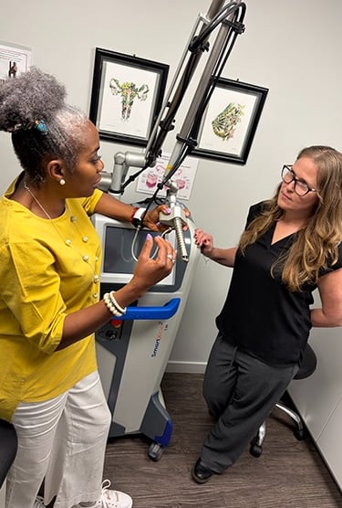 dr. aluko talking to female patient in front of monalisa touch equipment
