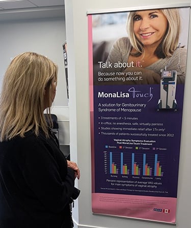 woman standing in doctors waiting room in front of a manalisa touch banner
