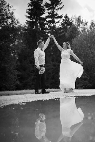a bride and groom holding hands in a puddle of water