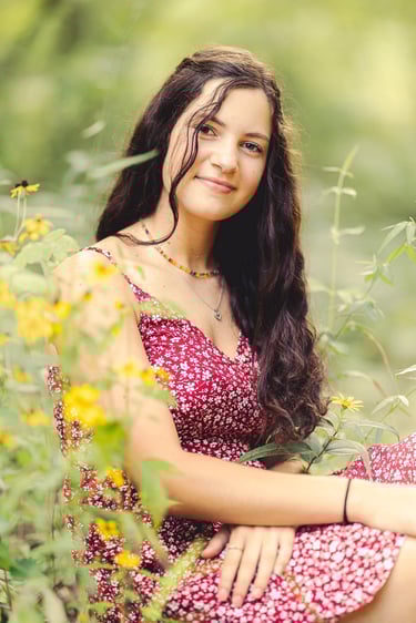a young lady in a red dress sitting in a field