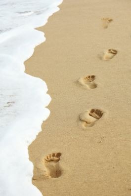 empreintes de pas sur le sable au bord de l’océan symbolisant le chemin en sophrologie humaniste