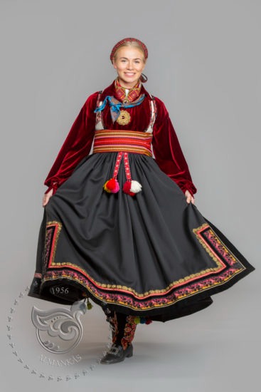 A woman in a bunad with a velvet shirt and wide belt