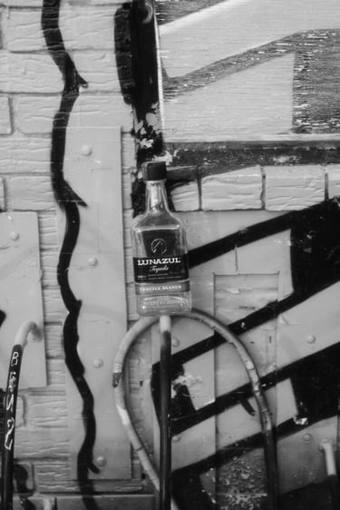 Black and white urban street art scene featuring a Lunazul Tequila bottle against a graffiti brick wall.