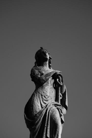 Black and white silhouette of an ancient stone angel statue against a clear dark sky.