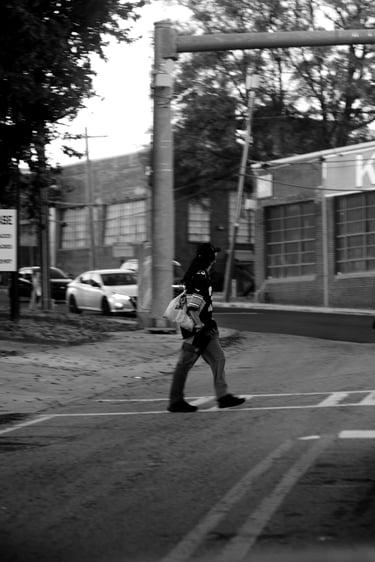 Black and white street photography of a person crossing a city road near the King Plow Arts Center.