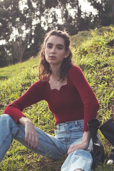 a woman sitting on a hill with a backpack