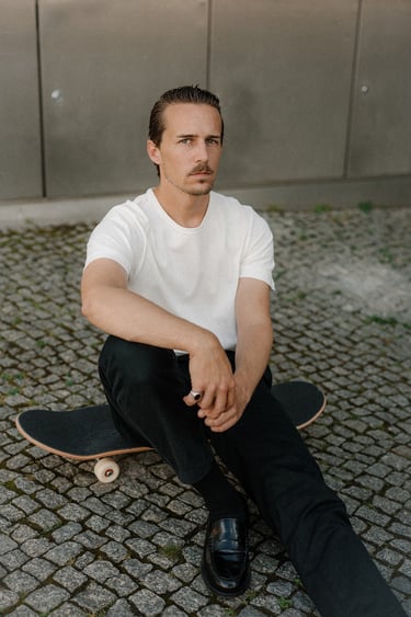 Portrait of artist and designer Philipp Schäfer sitting on a skateboard
