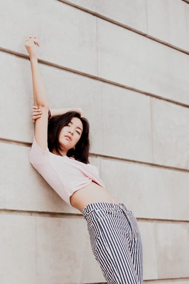 portrait de femme adossée contre un mur en pierre le bras en l'air couleur douces