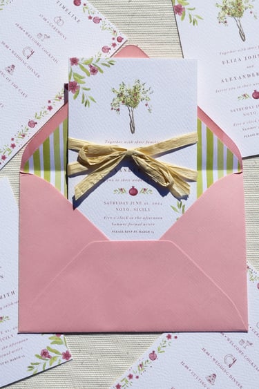 close up of invitation with pomegranate tree inside of pink envelope with stripped green lining