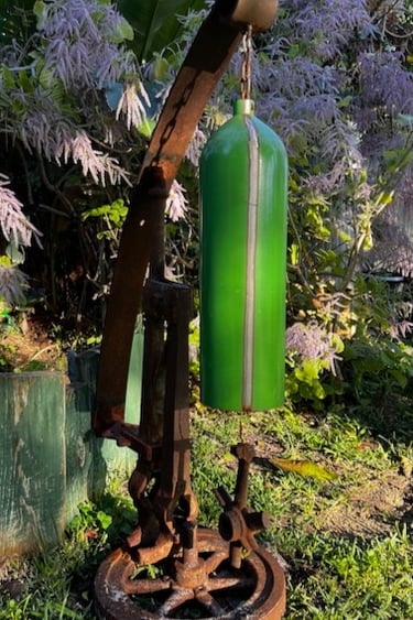 Rustic garden sculpture made from a green cylinder and recycled industrial iron parts.