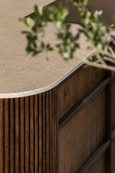 Detal meblarski: ryflowany front wyspy kuchennej i kamienny blat.