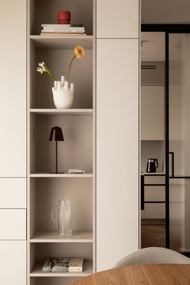 Detal regału: wazon w kształcie dłoni, lampka i książki na półce.