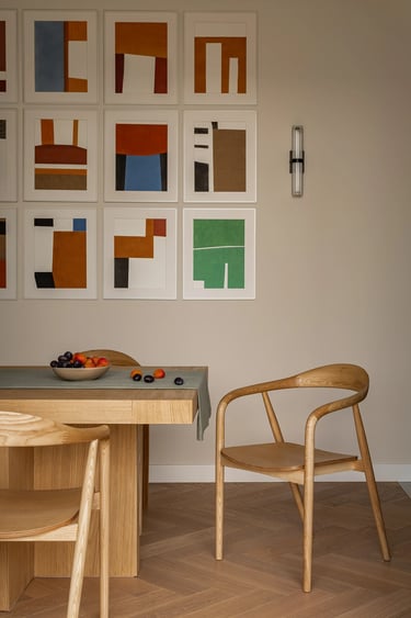 Realizacja wnętrza jadalni: drewniany stół, galeria ścienna i naturalne światło.