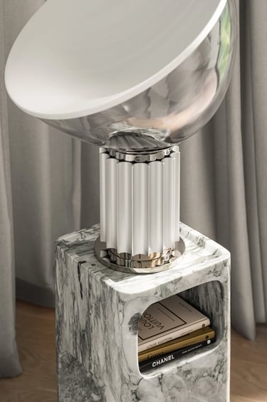 Luksusowy detal wnętrza: designerska lampa na marmurowym stoliku pomocniczym z książkami.