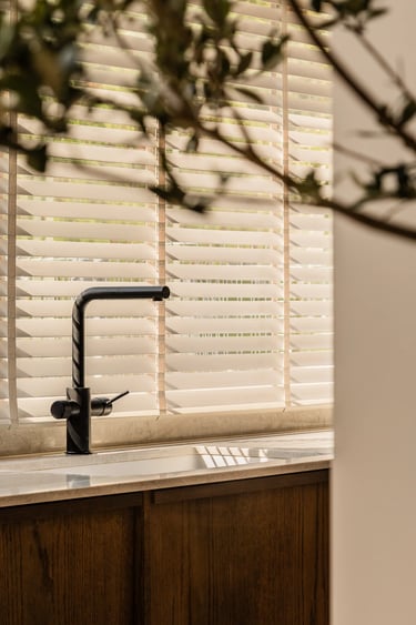 Kadr na strefę zmywania: czarna armatura i gra cieni z żaluzji.