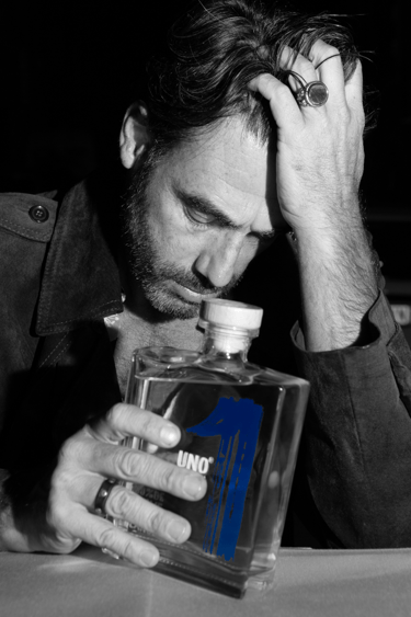 a man with a beard, holding a bottle of uno tequila blanco