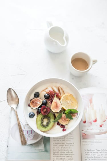 Cut fruits on a plate with tea and a magazine, illustrating a simple weekday self-care routine for mindfulness and wellness.