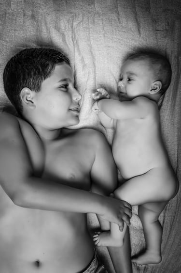 "Un retrato de familia en blanco y negro, hermano mayor y bebé acostados"