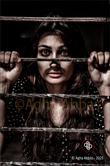 beautiful young girl captive behind bars, with eyes wide open in hope.