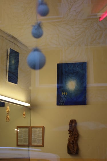 A blue abstract painting with glowing yellow text hangs on a warm yellow wall with modern art decor.