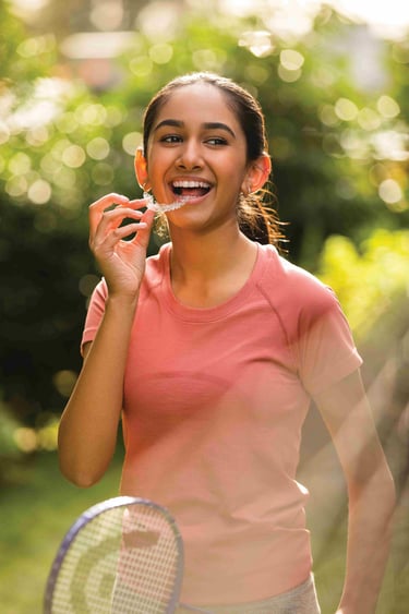 a woman holding a tennis racket and her clear aligners