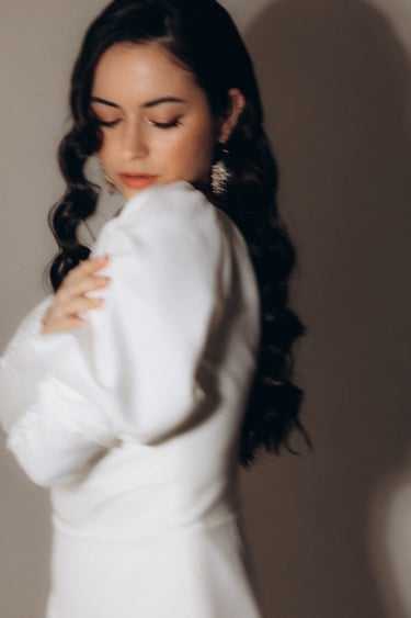 a woman in a white dress with long hair and earrings