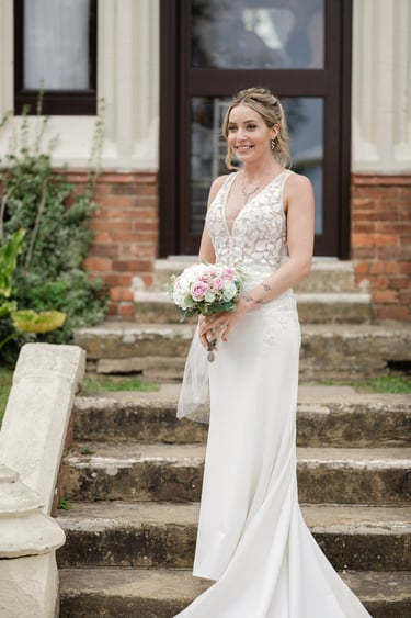 Bride snading in front of highley manor holding a bouquet 